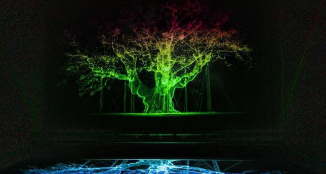 photo d'une projection sur un mur de la forme d'un arbre vert sur fond noir