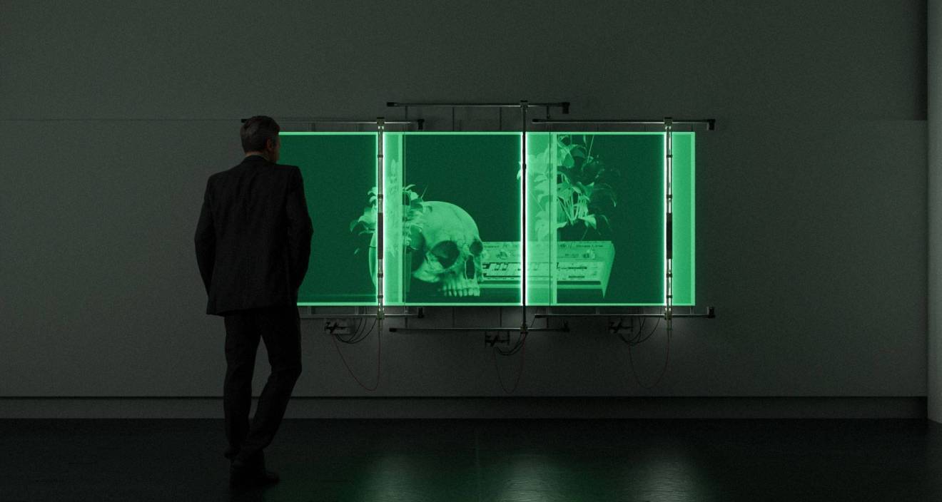 photo d'un écran vert avec un crâne et d'une personne de dos, dans le noir, en train de le regarder