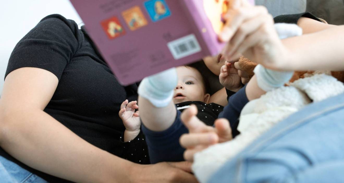 Un bébé et une famille lisent ensemble, promouvant l'amour et l'éducation. Cadre intérieur confortable.