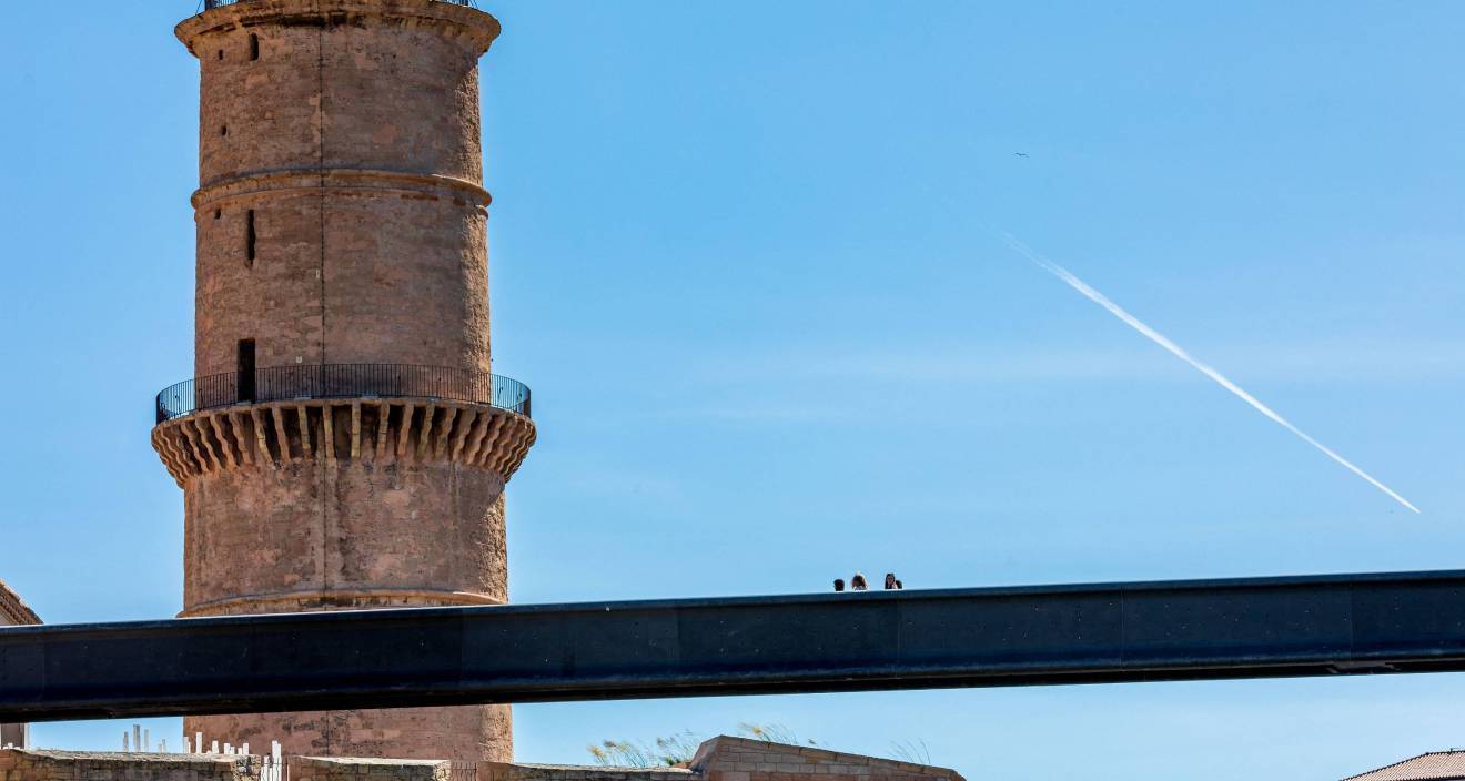 photo d'une tour extérieure sous un ciel bleu et d'une passerelle avec des personnes dessus