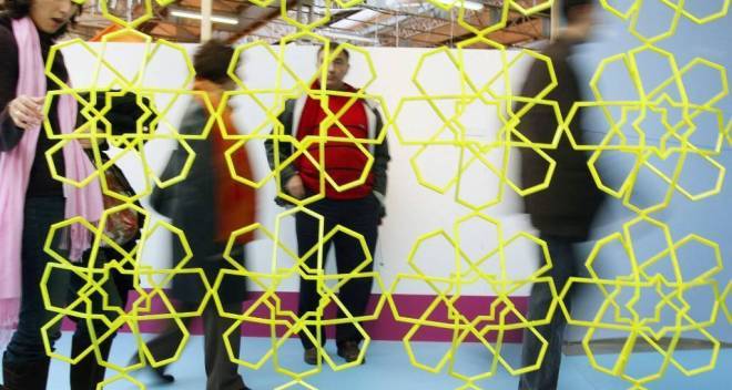 photo d'un mur ajouré avec des motifs jaunes et des personnes floues en arrière plan