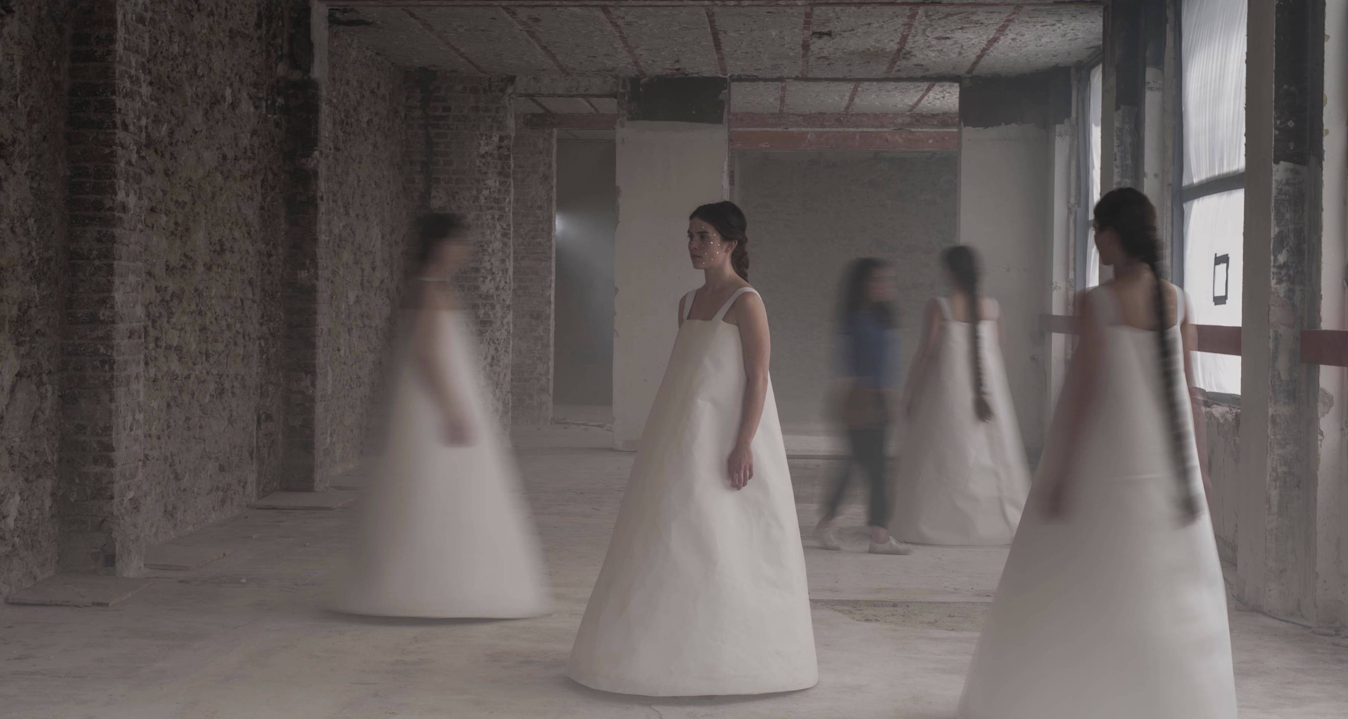 photo représentant 4 danseuses en robe blanche dans un décor industriel, image un peu floue