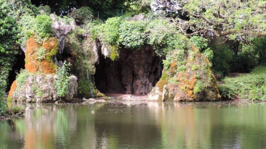 Etang au premier plan, à l'arrière plan une grotte qui surplombe l'étang