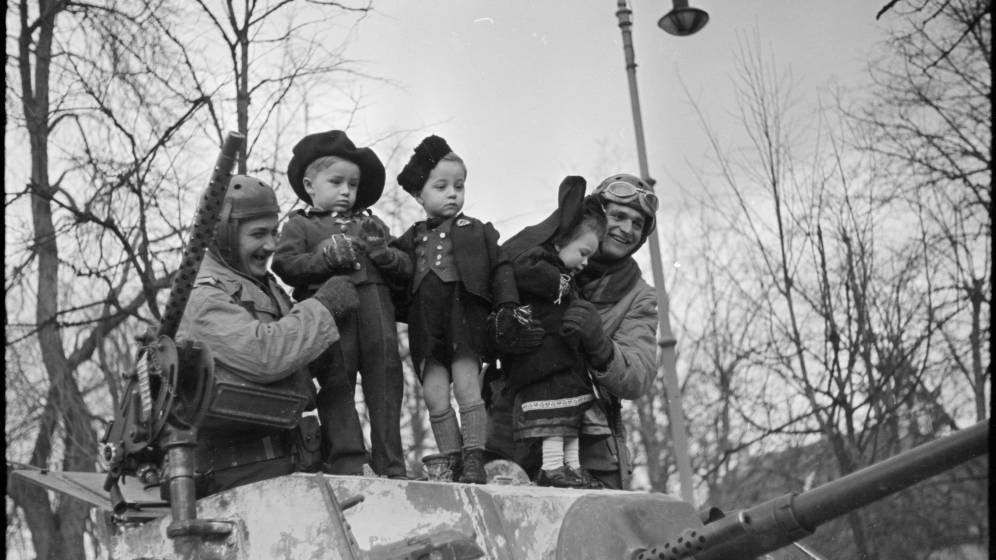 photo en noir et blanc soldat tenant enfants dans leurs bras sur un char
