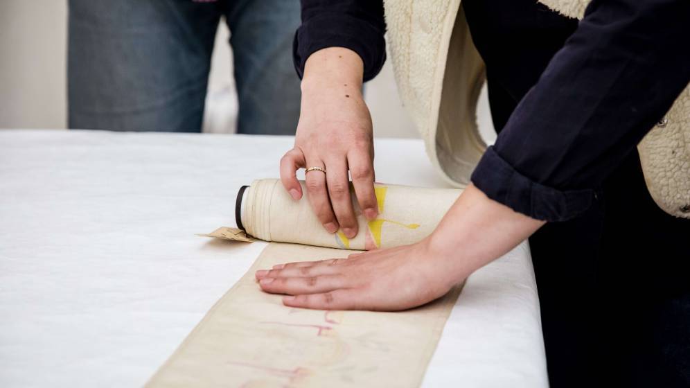 photo d'une personne déroulant une bandelette de torah - ou mappot - sur une table