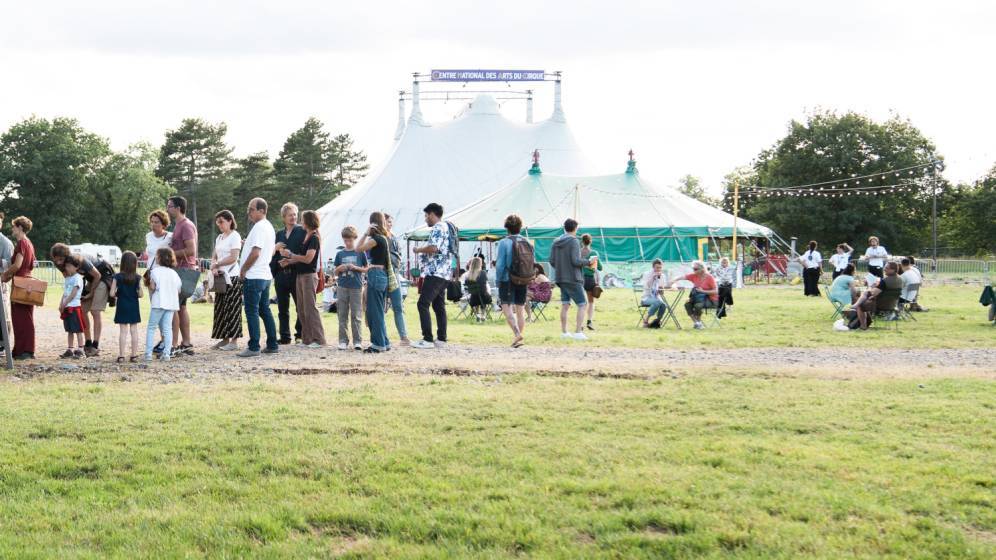 Un groupe de gens réunis devant des chapiteaux en plein air