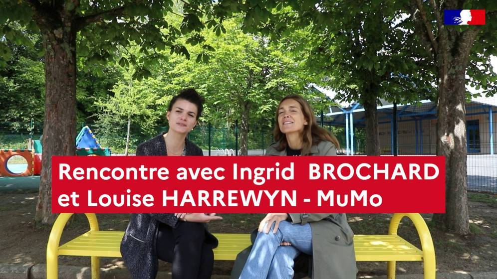 Visuel de l'épisode vidéo numéro 3. Le titre "Rencontre avec Ingrid BROCHARD et LouiseHARREWYN - MuMo" est placé au centre un peu vers le bas de l'image. En second plan sur un banc en métal jaune dans une cours d'école sont assises les deux intervenantes. En arrières plan, il y a des arbres, des jeux pour enfants à gauche et un préau donnant accès à des salles à droite.