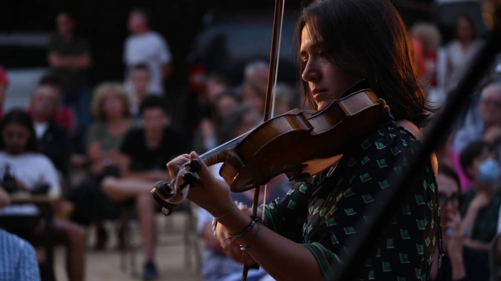 Jeune fille violoniste devant public estival (été culturel)