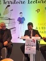 "Hilaire Multon, Directeur régional des affaires culturelles des Hauts-de-France, prononçant un discours lors de la signature du Contrat Territoire Lecture le 28 novembre 2024, à l’espace culturel La Faïencerie à Creil. Debout à un pupitre, il s’adresse à l’assemblée. En arrière-plan, un écran projette le visuel de l’événement avec le titre 'Signature du Contrat Territoire Lecture' et des illustrations représentant des scènes de lecture."