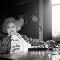 portrait de colette assise à une table avec un livre à la main, en noir et blanc