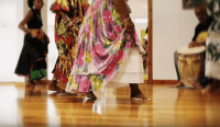 Femmes dansant le gwoka qui portent des joupes fleuries. Détail sur leurs jambes en mouvement.